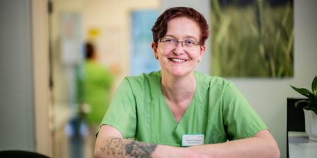 Weibliche Stationsleitung in grünem Kasak lächelt