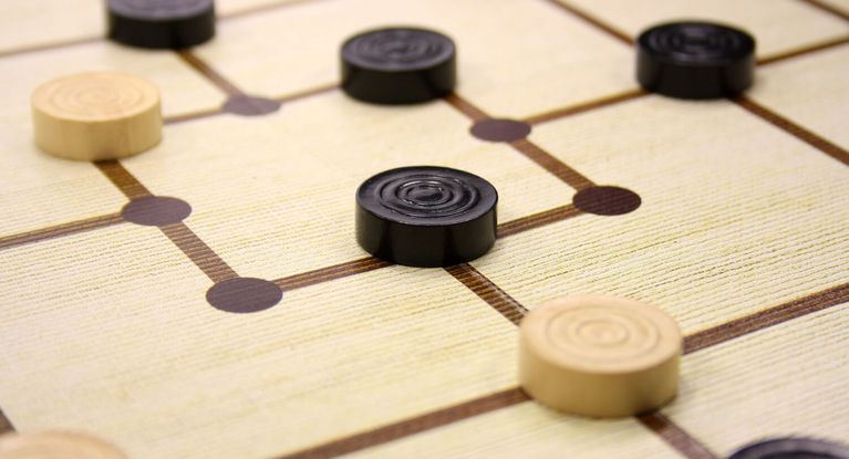 schwarze und weiße Mühlesteine auf einem Spielbrett