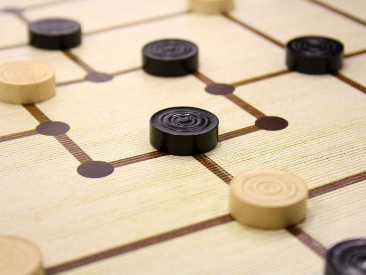 schwarze und weiße Mühlesteine auf einem Spielbrett