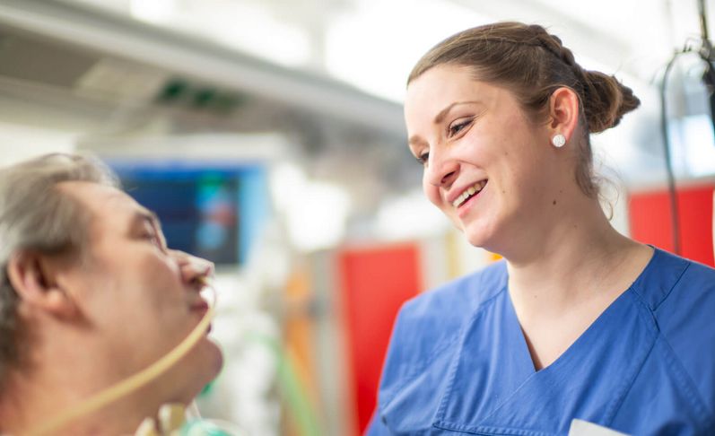 Pflegekraft spricht mit Patienten auf der Intensivstation