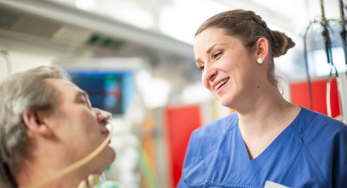 Pflegekraft spricht mit Patienten auf der Intensivstation