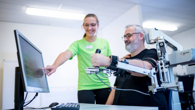 Therapeutin und Patient bei der Armtherapie mit Armeo