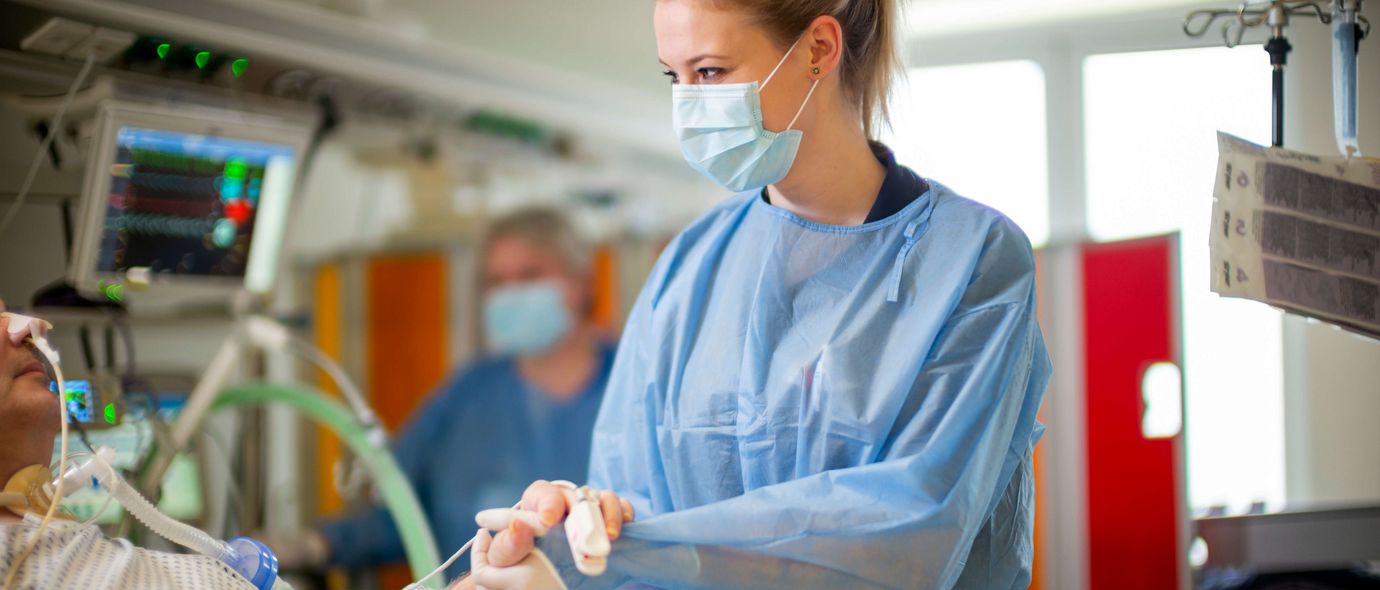 Pflegekraft hält eines Patienten auf der Intensivstation