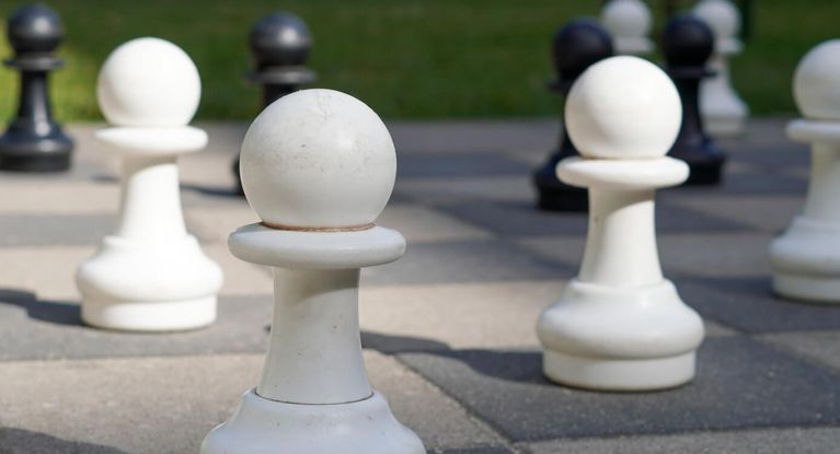 weiße Schachfiguren auf einem Außenschachspielfeld