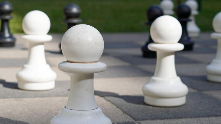 weiße Schachfiguren auf einem Außenschachspielfeld