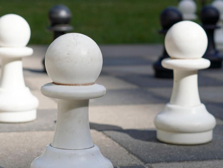 weiße Schachfiguren auf einem Außenschachspielfeld