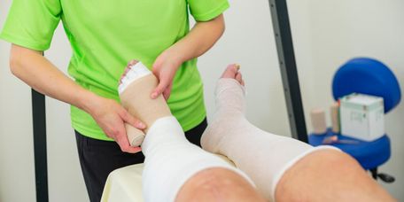 Therapeut verbindet Fuß zur Lymphdrainage