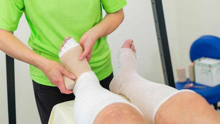 Therapeut verbindet Fuß zur Lymphdrainage