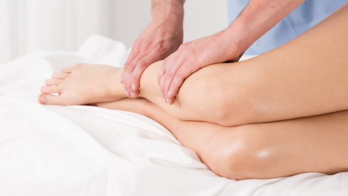 Physiotherapeut massiert Beine eines Patienten