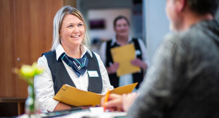 Patient trägt sich bei einer Rezeptionsdame in eine Liste an der Rezeption ein