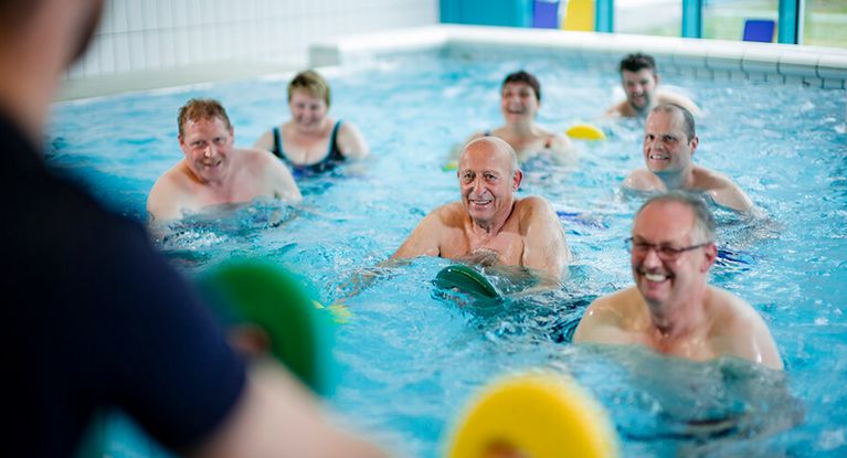 Eine Gruppe von Patienten trainiert gemeinsam im Schwimmbad