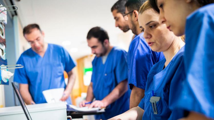 Ein Team aus Ärzten und Pflegekräften besprechen Patientenakten