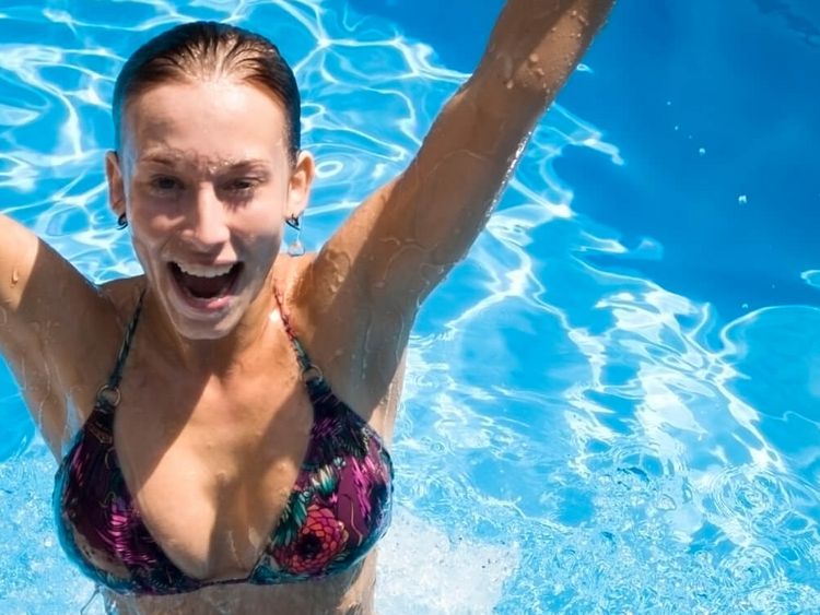 Eine Frau badet im Pool und springt hoch