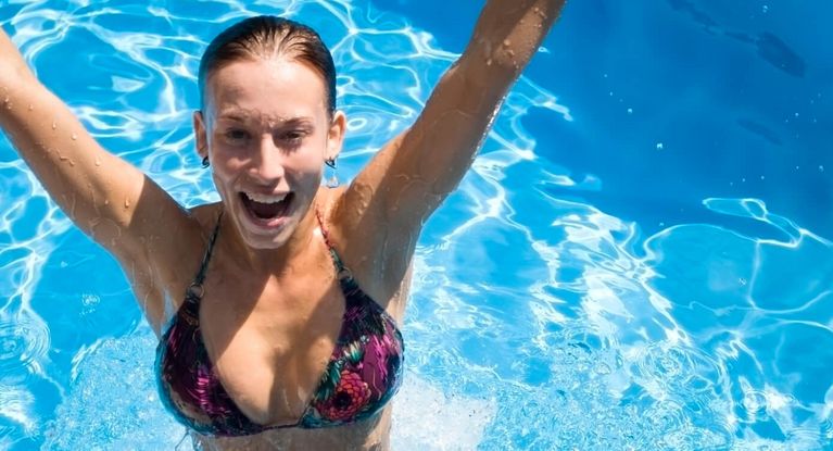 Eine Frau badet im Pool und springt hoch