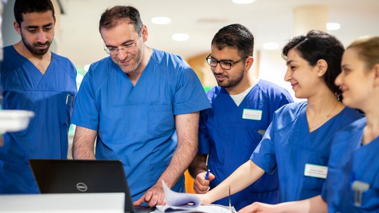 Ein Team aus Ärzten und Pflegekräften besprechen Patientenakten