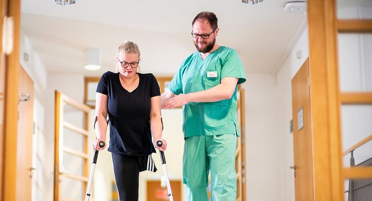 Therapeut untertützt Patientin bei der Gangschule für Amputierte