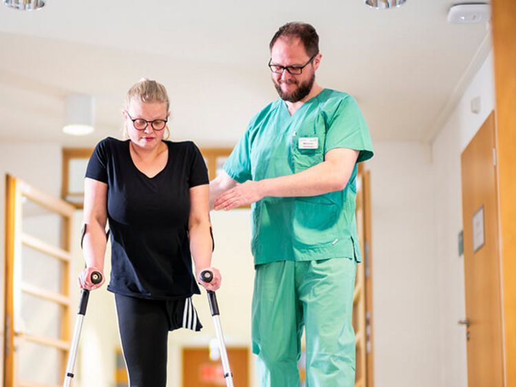 Therapeut untertützt Patientin bei der Gangschule für Amputierte