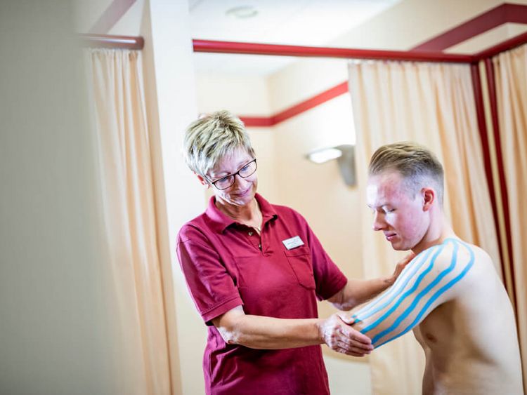 Therapeutin behandelt Patienten mit Kinesio Tape